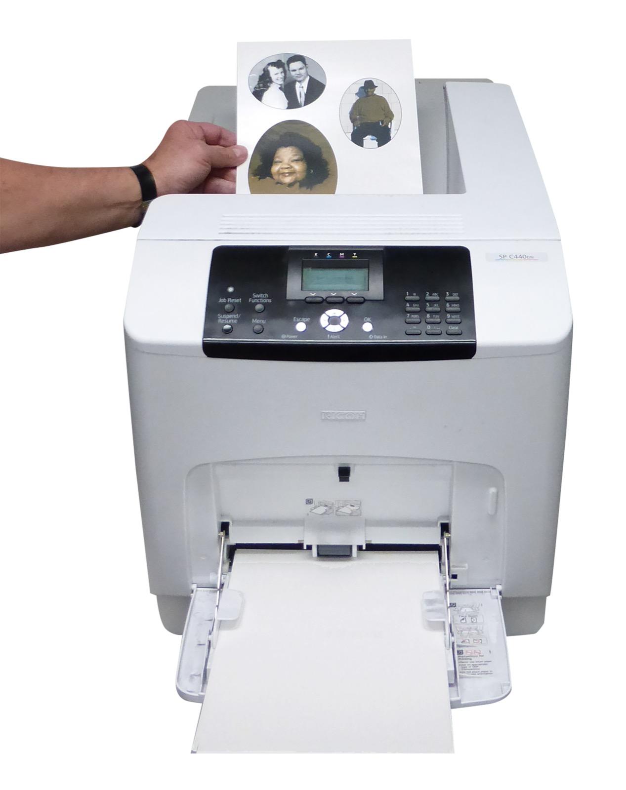 Hand lifting a printed sheet of porcelain portrait decals from the top tray of a Ricoh ceramic decal printer
